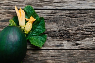 Ahşap zemin üzerinde çiçekler olan taze kabak.