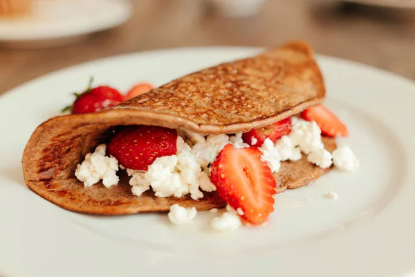 Pancakes with ricotta cheese and fresh strawberries on a white plate, close up. — Stock Photo, Image