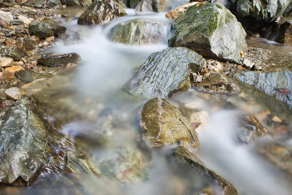 Галька или камни в ручье или ручье текучей воды — стоковое фото