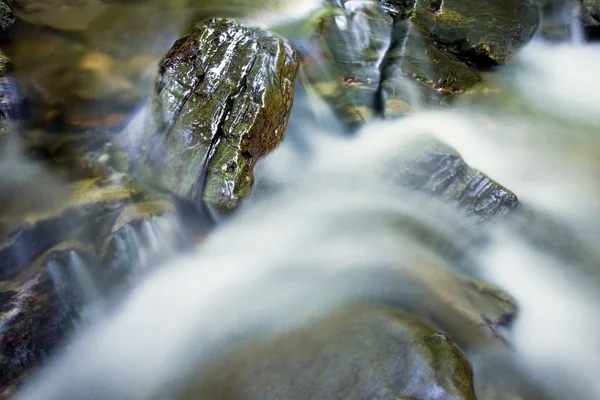 Вода падает над камнями — стоковое фото