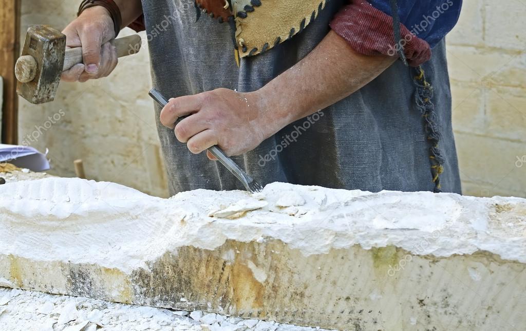Stonemason working on a cube of sandstone