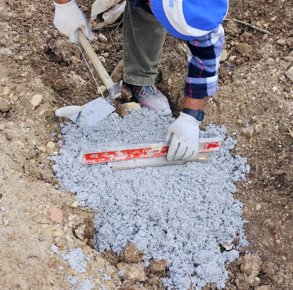 Worker puts plan a level to the foundation of the sidewalk — Stock Photo, Image