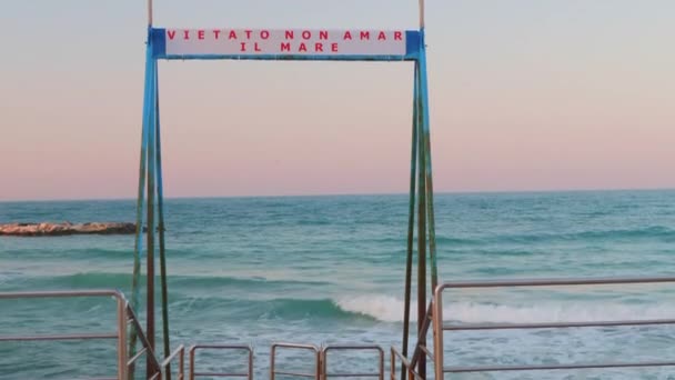 イタリアのバーリにあるビーチでの小さな桟橋 看板には 海を愛さない という素敵なフレーズがあります — ストック動画