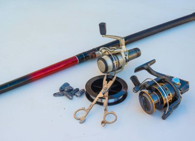 Fishing rod and spinnings in the composition with accessories for fishing on the old background on the table