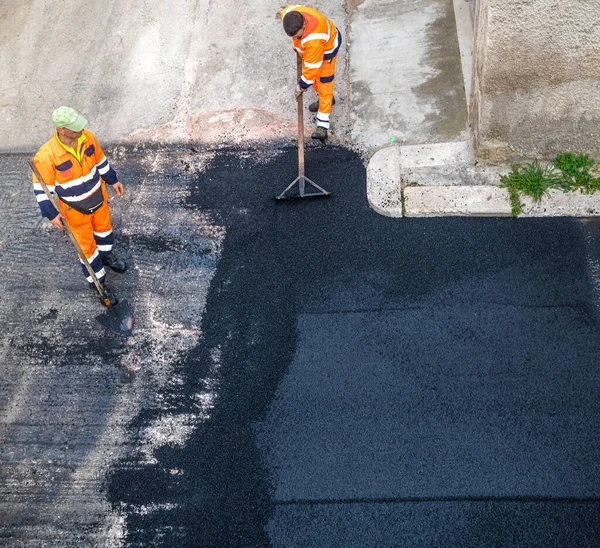 Worker on Asphalting paver machine during Road street repairing works