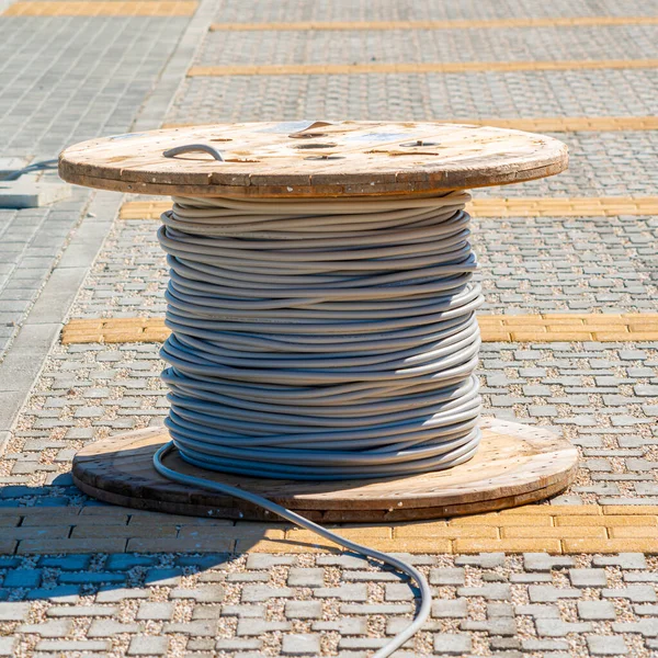 Wire electric cable with wooden coil of electric cable waiting to be slipped into the conduit
