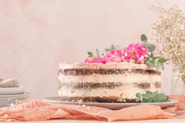 Taze güllerle çikolatalı, çıplak pasta ve beyaz arka planda İsviçre tereyağı.