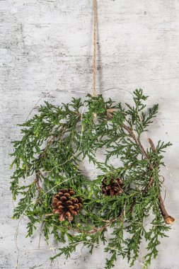 Yeşil dallı Noel çelengi, çam kozalakları ve doğal festival süslemeleri. Duvarda Rustik Noel çelengi asılı. Mevsimlik tatil geliri