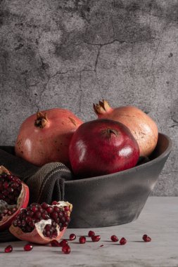 Modern tasarım siyah seramik kâse. Koyu tezgah ve arka planda nar meyvesi..