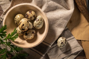 Seramik kasede taze bıldırcın yumurtası, kahverengi ahşap masa. Mutfak arka planında çiğ bıldırcın yumurtası. Yemek pişirme hazırlığı kavramı