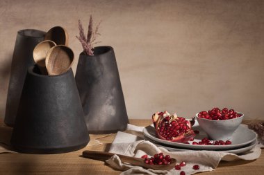 Modern koyu seramik vazolarla dekore edilmiş mutfak tezgahındaki seramik kasede lezzetli olgun nar çekirdekleri. Metin için boşluk