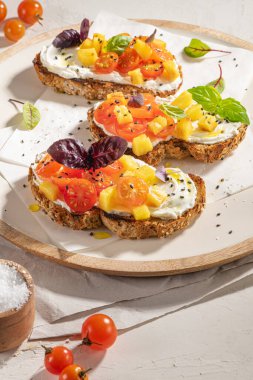 Kızarmış domatesli İtalyan bruschetaları, krem peynir, ananas dilimleri ve mutfak tezgahında otlar. Hizmet etmeye hazır