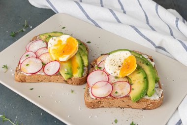 Avokado turp peynirli sandviçler ve koyu arkaplanda çavdar ekmeği üzerinde yumurtalar. Sağlıklı kahvaltı. Vejetaryen yemeği..