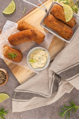 Sarımsaklı mayonezli et kroketleri mevsim için limon dilimleri ve mutfak tezgahındaki ahşap masada biberiye yaprakları..