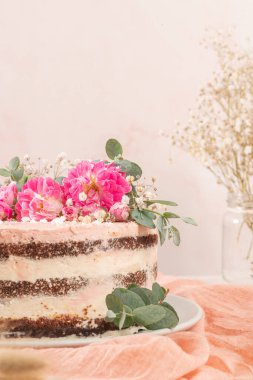 Taze güllerle çikolatalı, çıplak pasta ve beyaz arka planda İsviçre tereyağı.