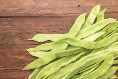 Çiğ yeşil fasulye yakın plan. Taze yeşil fasulye olarak da bilinir. Fasulye, fasulye, fasulye, mısır gevreği ve taricotlar ahşaba dönüşür.