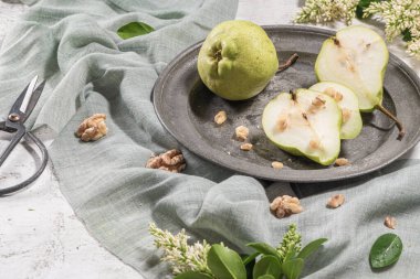 Fındık ile lezzetli armut. Çiçeklerle süslenmiş bir masa ve plakaya kesilmiş bir tabak armut