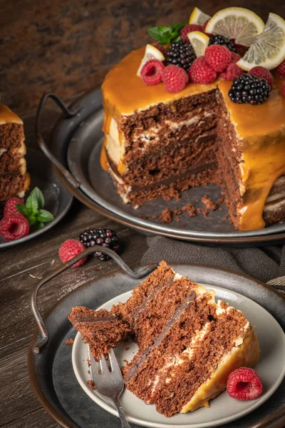 Karamel soslu, böğürtlen ve ahududu ile süslenmiş lezzetli yarı çıplak çikolatalı pasta. Koyu arkaplan