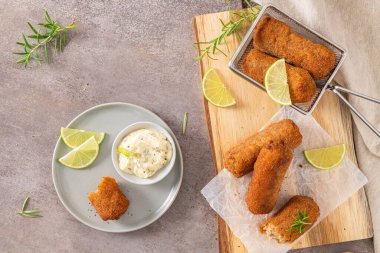 Sarımsaklı mayonezli et kroketleri mevsim için limon dilimleri ve mutfak tezgahındaki ahşap masada biberiye yaprakları..