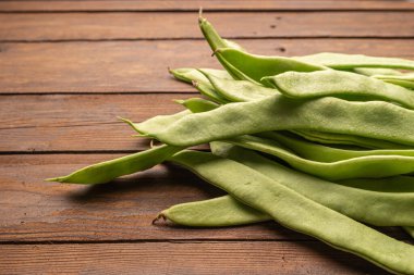 Çiğ yeşil fasulye yakın plan. Taze yeşil fasulye olarak da bilinir. Fasulye, fasulye, fasulye, mısır gevreği ve taricotlar ahşaba dönüşür.