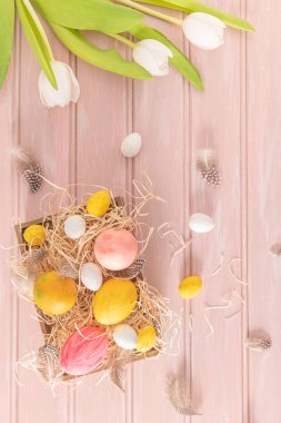 Ahşap kutuda ve beyaz lalelerde Paskalya pembesi, sarı ve beyaz yumurtalar