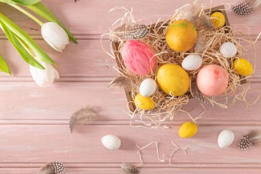 Ahşap kutuda ve beyaz lalelerde Paskalya pembesi, sarı ve beyaz yumurtalar