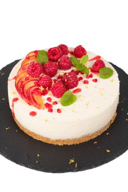 Beyaz zemin üzerinde ahududu, erik ve nane yapraklı cheesecake.