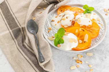 Yoğurt ve badem ile dilimlenmiş Trabzon hurması. Sağlıklı gıda kavramı üzerinde açık renkli. üstten görünüm