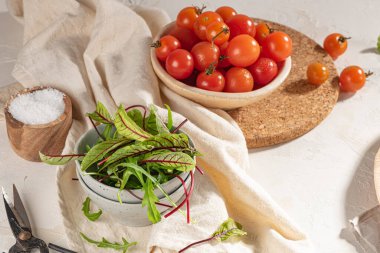 Kâse ve kiraz domateslerinde taze kuş yaprakları. Kırmızı damarlı kuş. Seramik kasede mikro yeşil. Rumex Sanguineus salata hazırlıyor.