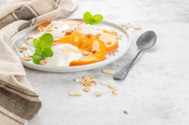 Yoğurt ve badem ile dilimlenmiş Trabzon hurması. Sağlıklı gıda kavramı üzerinde açık renkli. üstten görünüm