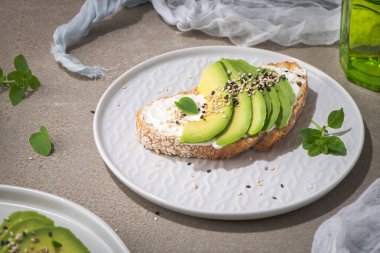 Healthy toast with avocado cream cheese and wheat bread on a plate. Delicious snacks and avocado sandwiches. Food composition, tasty Italian meal.