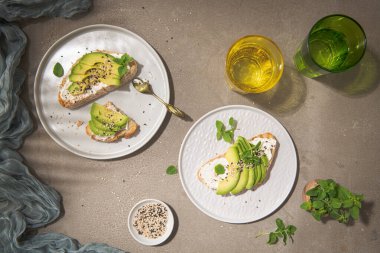 Avokado krem peynirli sağlıklı tost ve tabakta buğday ekmeği. Lezzetli atıştırmalıklar ve avokado sandviçleri. Yemek kompozisyonu, lezzetli İtalyan yemeği..