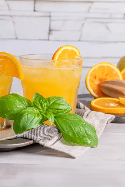 Healthy juice from oranges with basil leaves in glass, selective focus