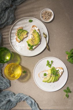 Avokado krem peynirli sağlıklı tost ve tabakta buğday ekmeği. Lezzetli atıştırmalıklar ve avokado sandviçleri. Yemek kompozisyonu, lezzetli İtalyan yemeği..