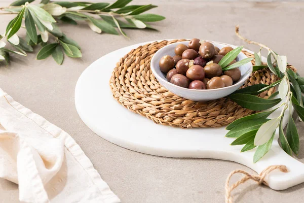 Olives with olive leaves in ceramic bowl on kitchen countertop