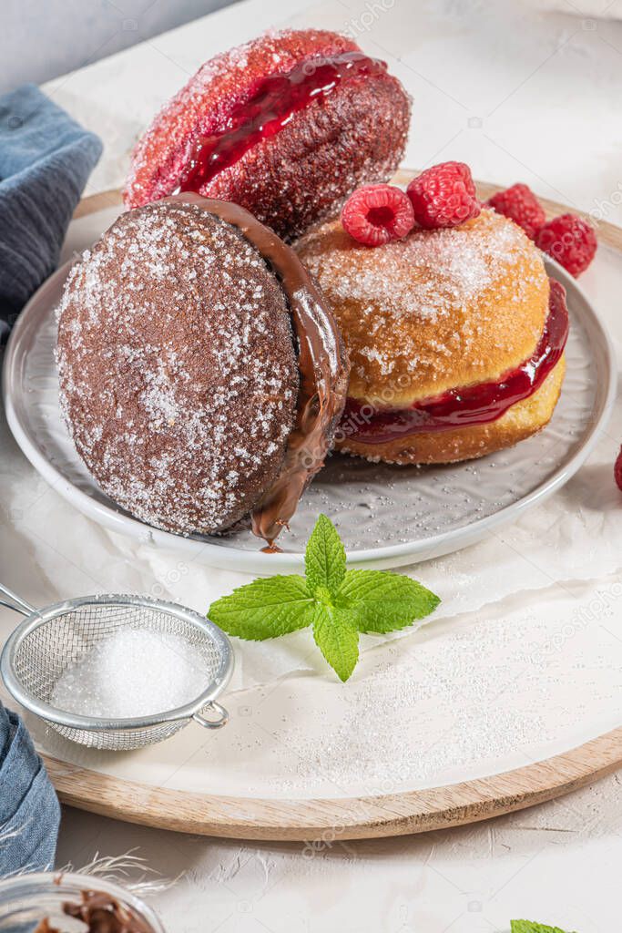 Bolas de Berlim, or Berlin Balls. Portuguese fried dough with sugar, Filled with chocolate or raspberry jam. Portuguese fried dough with sugar. Chocolate and  beetroot  berliner Pancakes Doughnuts Donuts stuffed with various creams