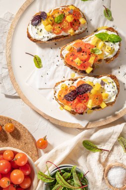 Kızarmış domatesli İtalyan bruschetaları, krem peynir, ananas dilimleri ve mutfak tezgahında otlar. Hizmet etmeye hazır