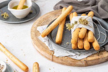 Breadsticks grissini. Bread sticks with sesame seeds, oregano and olive oil and balsamic vinegar on kitchen countertop.
