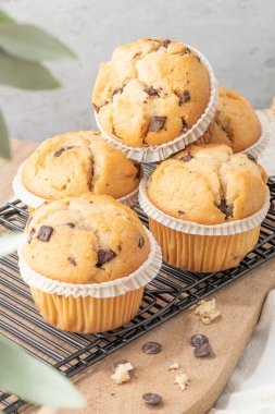 Chocolate chip muffins on a baking rack and glasses of milk on a white kitchen countertop.  Morning breakfast table