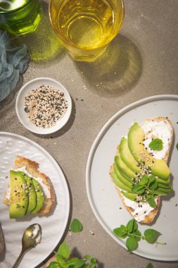 Avokado krem peynirli sağlıklı tost ve tabakta buğday ekmeği. Lezzetli atıştırmalıklar ve avokado sandviçleri. Yemek kompozisyonu, lezzetli İtalyan yemeği..