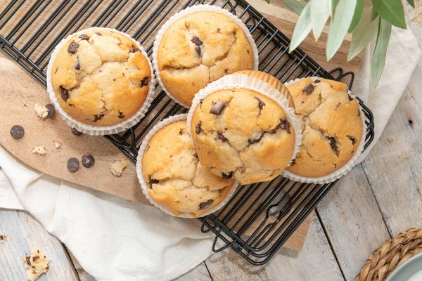 Chocolate chip muffins on a baking rack and glasses of milk on a white kitchen countertop.  Morning breakfast table. Top view, flat lay