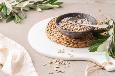 Mutfak tezgahında kaşıkla seramik bir kasede soyulmuş ayçekirdeği. Sağlıklı yemek ve diyet kavramları için..