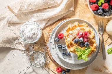 Geleneksel Belçika waffleları, mutfak tezgahına taze ahududu ve yabanmersini serpiştirilmiş pudra şekeri serpiştirilmiş..