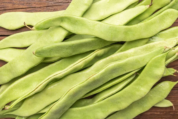 Raw green beans closeup. Fresh green bean also known as french beans, string beans, snap bean, snaps and haricots vert on wooden