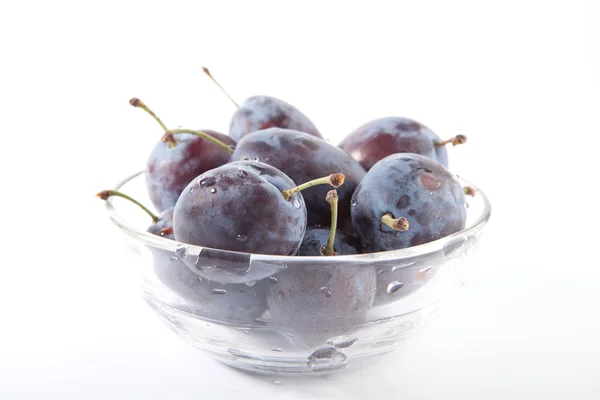 Prunes dans un bol en verre isolé sur le fond blanc — Photo