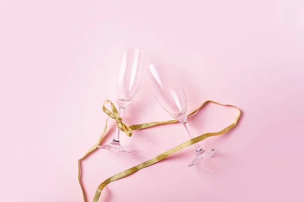 Dois copos de champanhe e fita em um fundo rosa. Conceito de celebração. — Fotografia de Stock