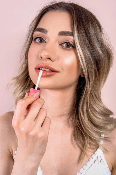 Açık pembe arka planda doğal makyajı olan güzel sarışın kız, elinde ruj, fotokopi odası var.