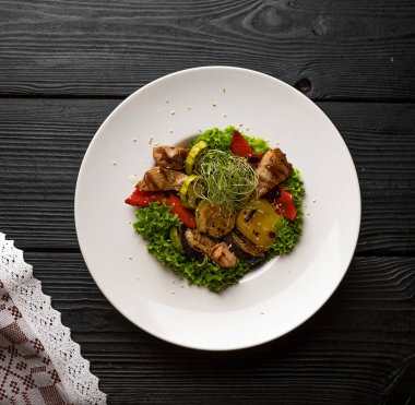 Sebzeli ve etli sıcak salata, beyaz tabakta servis edilir.