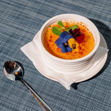 creme brulee tatlısı çiçeklerle süslenmiş, mavi arka planda