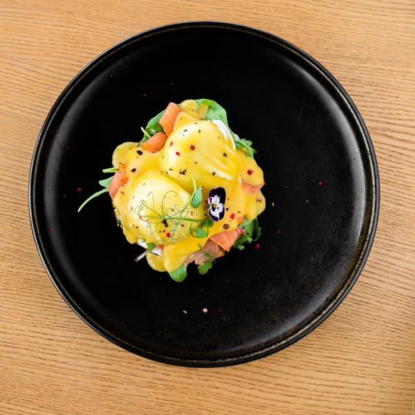 Tahta masada siyah tabakta kırmızı balık ve peynir tabağı.